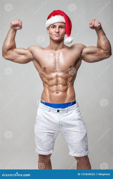 Muscular Naked Guy With A Naked Torso In A Hat Santa Claus Shows Biceps