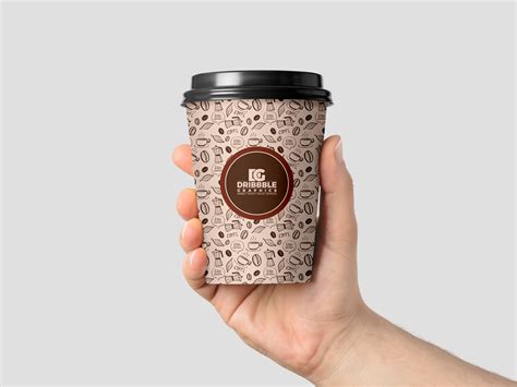 It showcases a coffee cup with a straw set on a wooden surface next to a paper bag with a fun background. Free Hand Holding Coffee Cup Mockup For Branding 2018 ...
