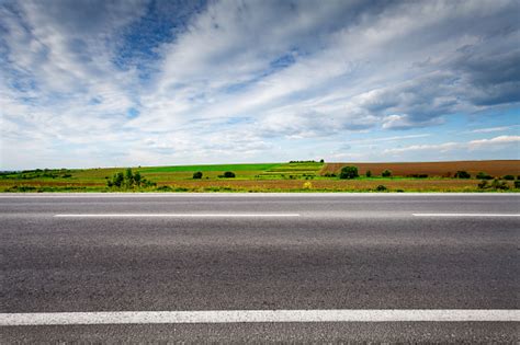 Country Road With Field On Horizon Side View Stock Photo Download