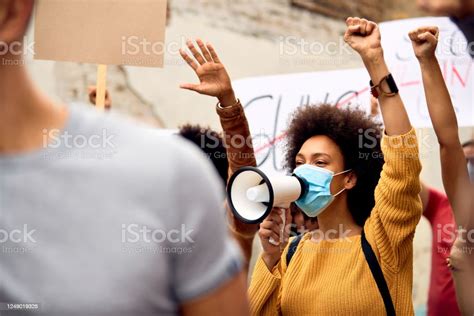 Young Black Woman Wearing Protective Face Mask While Shouting Through Megaphone On Antiracism
