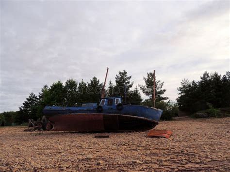 An Old Fishing Boat Washed Up On The Pebbly Shore Of The Lake Stock