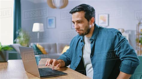 Portrait Of Handsome Young Man Using Laptop Computer At Home Making A