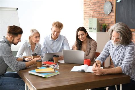 Business People Discussing Work Matters At Table In Office Stock Photo