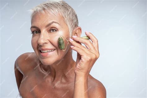 Premium Photo Beautiful Mature Lady Using Jade Roller On Her Face Leaning To The Camera