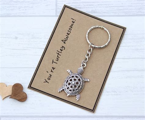 A Keychain With A Turtle On It Sitting Next To A Heart Shaped Card