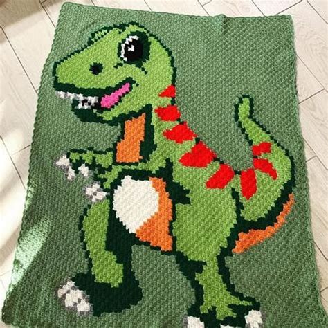 A Crocheted Dinosaur Blanket On The Floor