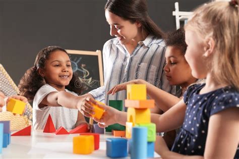 Cute Little Children And Nursery Teacher Playing With Building Blocks