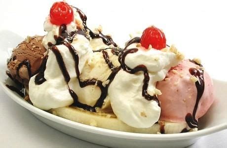 Three Scoops Of Ice Cream And Banana Split On A White Plate With Cherries