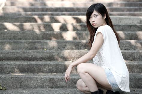 cute asian woman in a white top squatting down on steps stock image image of forward clean