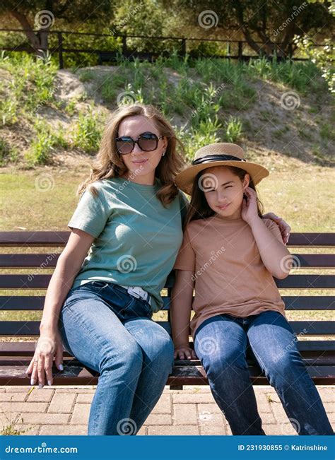 Mother And Daughter Sitting On The Wooden Bench In Park Stock Image