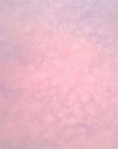 An Airplane Is Flying In The Sky With Pink Clouds Behind It On A Sunny Day