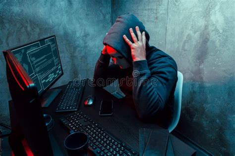Anonymous Internet Hacker With Mask Sitting At The Table And Using