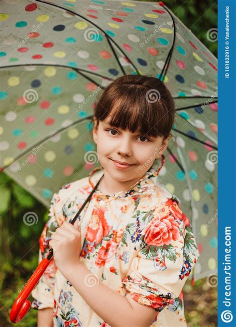 A Beautiful Girl In A Bright Raincoat Walks During The