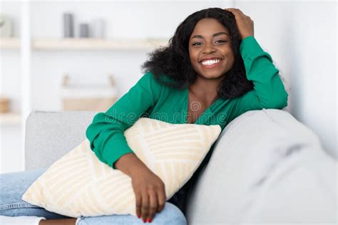 Smiling Pretty African American Woman Sitting On Couch At Home Stock