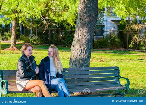 Beautiful Women Sitting On Bench In Sunny Autumn Day In The Park Stock