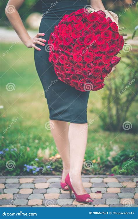 fashion beautiful woman is wearing black dress is holding big bouquet of 101 red roses stock