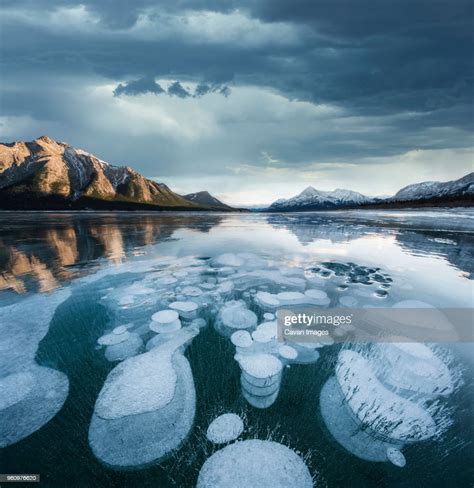 Majestic View Of Methane Bubbles In Abraham Lake By Mountains Against