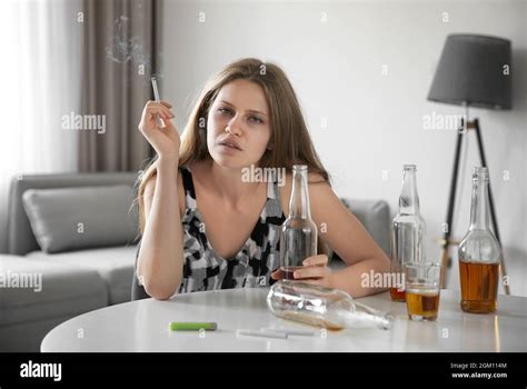 Young Woman Drinking Alcohol And Smoking Cigarette At Home Stock Photo
