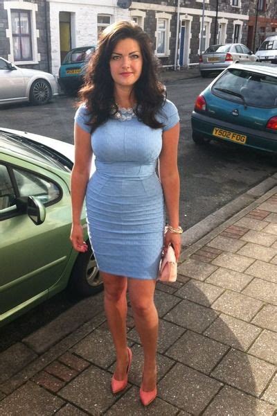 A Woman In A Blue Dress Standing Next To A Car