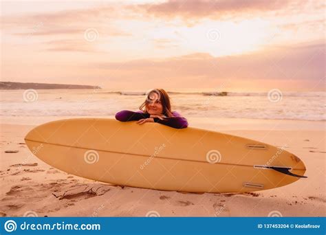 Smiled A Surfer Girl With Surfboard On A Beach At Sunset Stock Photo