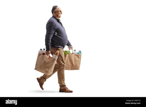 Full Length Profile Shot Of A Mature Man Carrying Grocery Bags And Walking Isolated On White