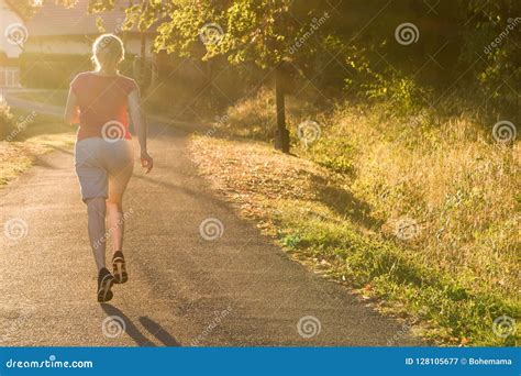 Athletic Woman Running At A Countryside Trail In Sunrise Light Stock
