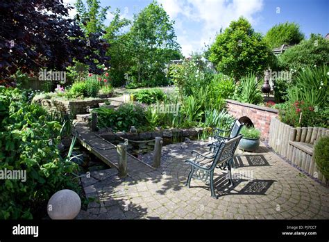 Beautiful Landscaped Garden With Bridge Over The Pond Paved Area