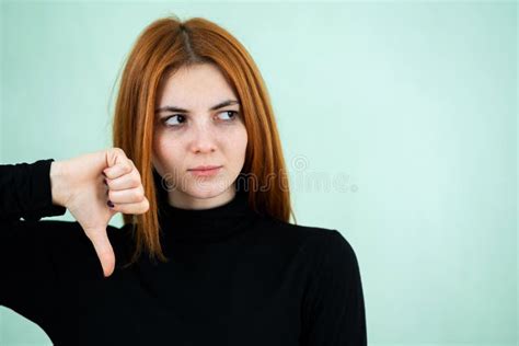 Sad Dissatisfied Redhead Girl Showing Thumbs Down Sign With Her Fingers