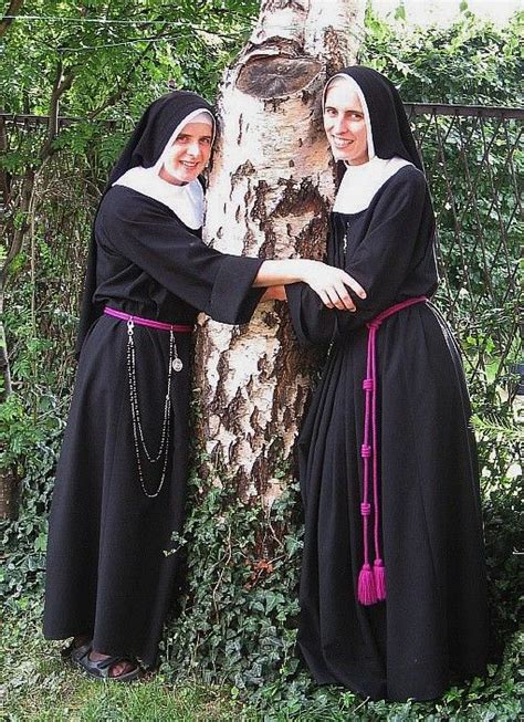 Two Women Dressed In Black Standing Next To A Tree