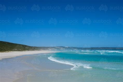 Image Of Sole Person Swimming In Remote Ocean With Beach And Grassy