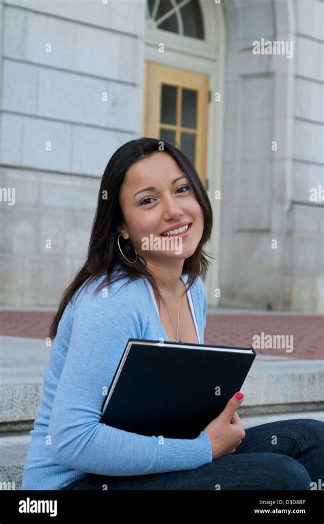 Hispanic Female College Student With Textbook On University Campus
