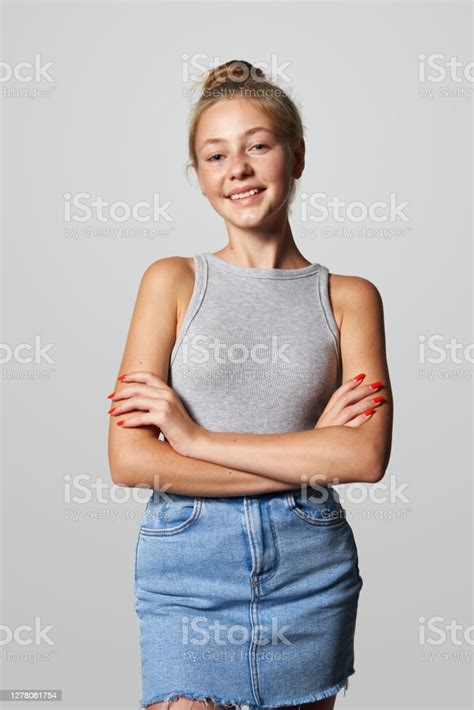 Beautiful Woman In Blue Denim Skirt Standing On White Wall Background