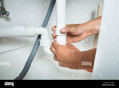 Plumber Working On Pipes Under Kitchen Sink Stock Photo Alamy