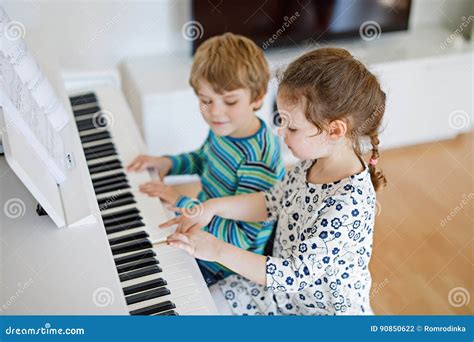 Two Little Kids Girl And Boy Playing Piano In Living Room Or Music
