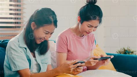jovem casal de mulheres lgbtq lésbicas usando telefone celular em casa amante asiática feliz