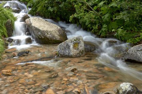 Waterfall And Clear River In A Mountain Stream In A Green Rocky Forest