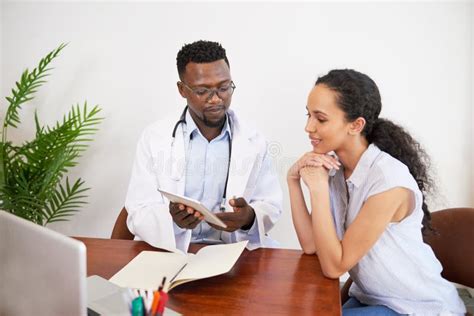 Black Male Doctor And Female Patient Discuss Labwork Results At Doctor