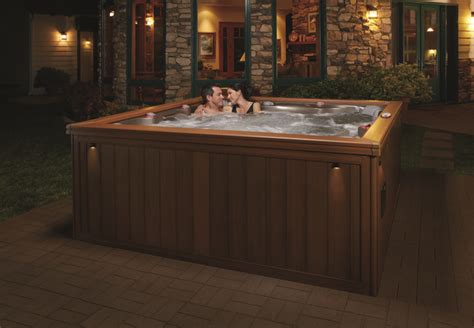 Two People Sitting In An Outdoor Hot Tub At Night With Lights On The