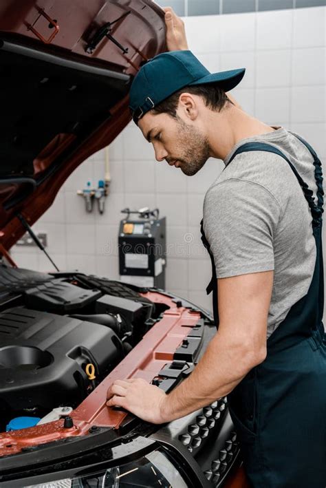 Side View Of Repairman Examining Car With Opened Cowl Stock Photo