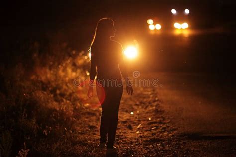 Silhouette Of Young Slender Woman In The Backlight Of Car Headlights On
