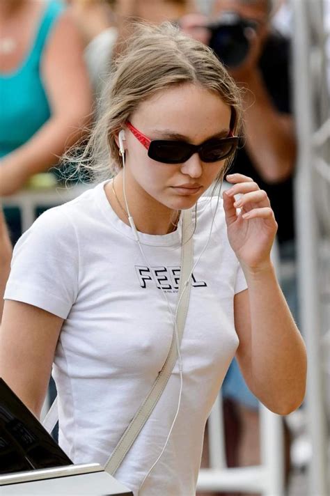 A Woman Wearing Sunglasses And Headphones Walking Down The Street