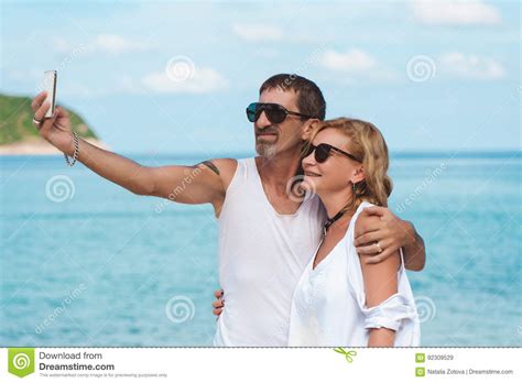 Portrait Of Mature Smiling Couple Taking A Selfie At The Beach Stock