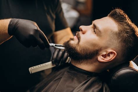 Free Photo Handsome Man Cutting Beard At A Barber Shop Salon