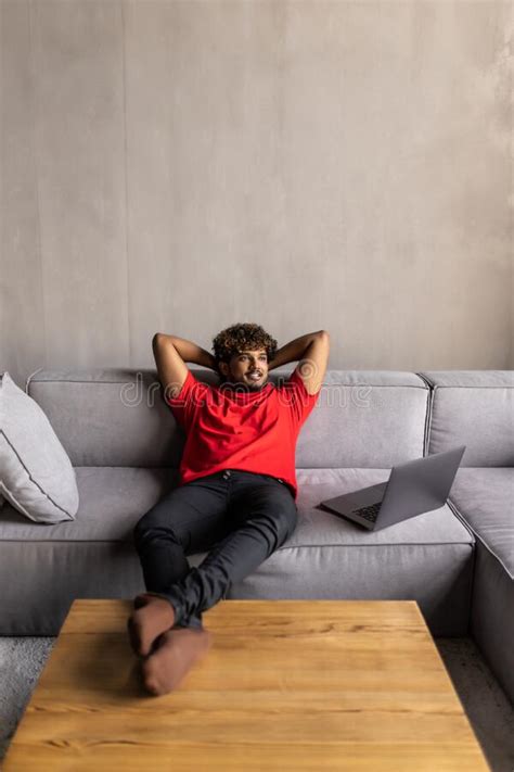 Satisfied Relaxed Young Indian Man Chilling On Sofa In Living Room