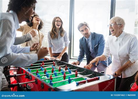 Employees Playing Table Soccer Indoor Game In The Office During Break