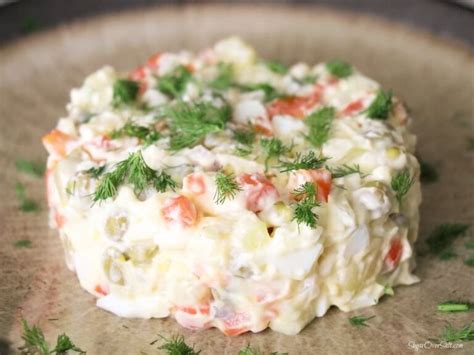 A Potato Salad With Tomatoes And Dill Sprinkled On Top