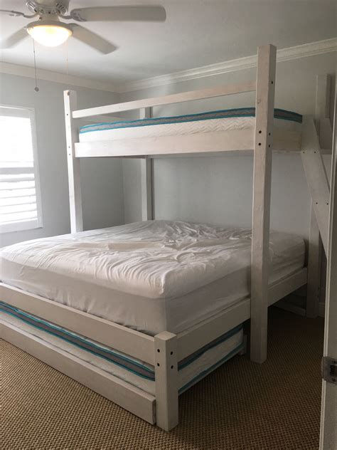 A White Bunk Bed Sitting In A Bedroom Next To A Window With Blinds On