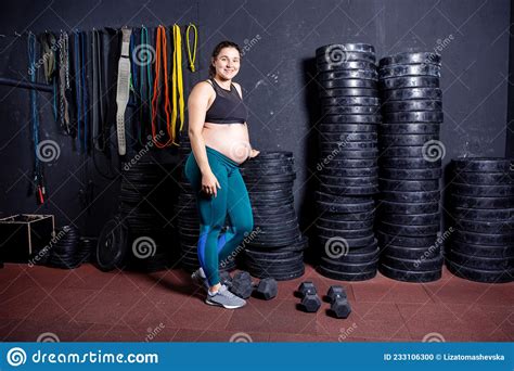 Strong Pregnant Woman Posing With Dumbbells In Her Hands Against