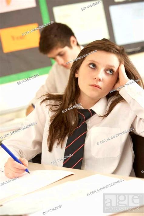 Bored Female Teenage Student Studying In Classroom Stock Photo