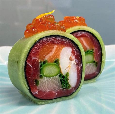 Two Sushi Rolls With Cucumbers And Salmon On Them